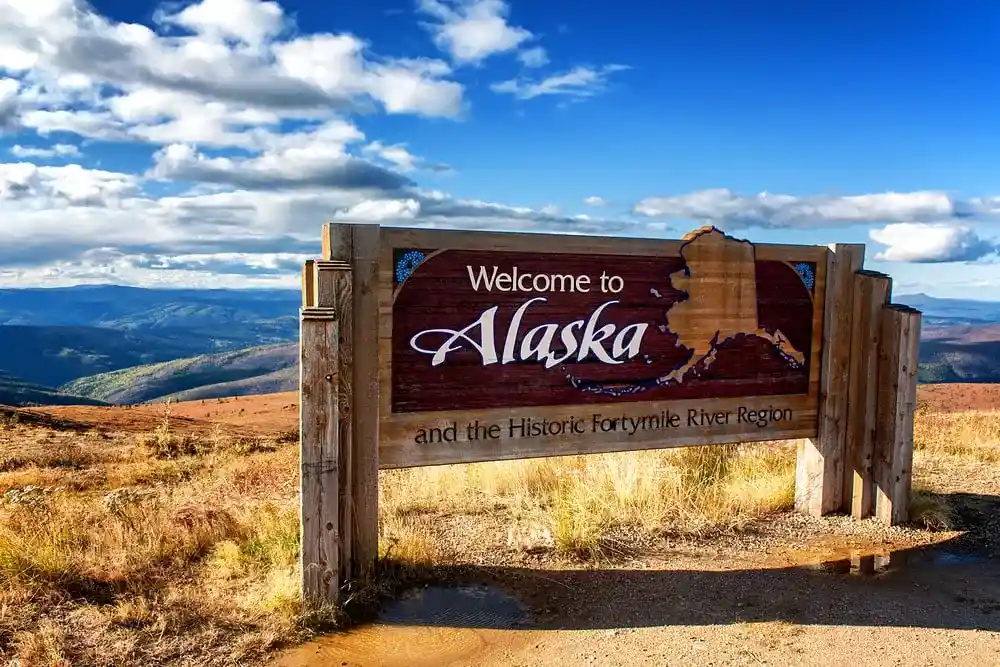 A “Welcome to Alaska” sign overlooking a beautiful valley