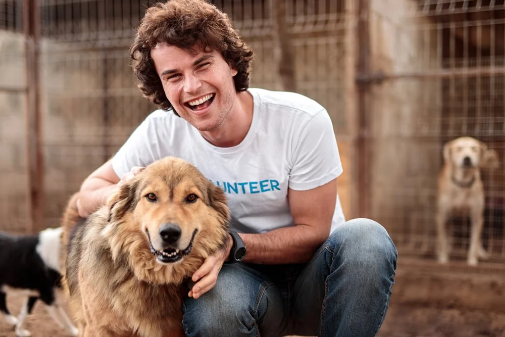 Volunteer posing with a dog at an animal shelter