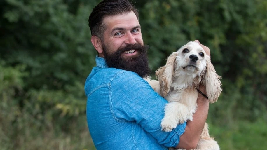 A man holds his long-eared dog in his arms while outside.