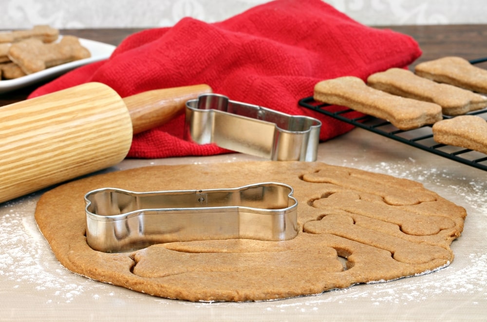 Dog biscuit dough rolled out with a rolling pin and cut out with bone-shaped cookie cutter