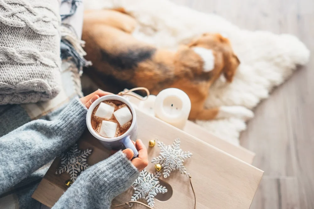 Woman with a cup and marshmallows, and a dog at her feet