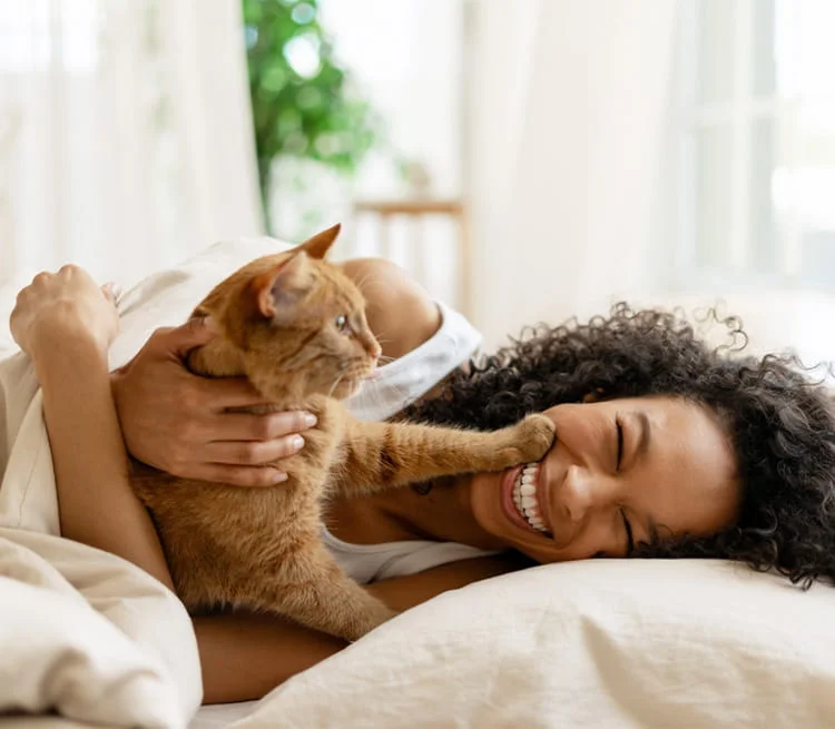 A woman cuddling with her cat on the floor