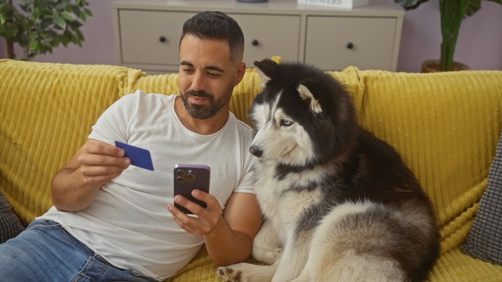 Man sitting with his dog and looking at his credit card