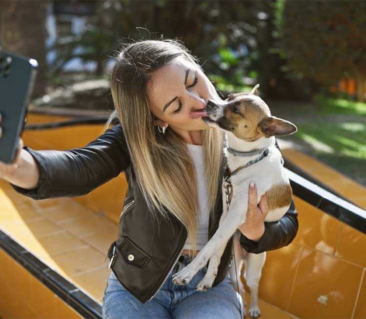 woman taking a selfie as her dog licks her face