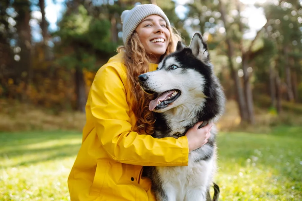 woman cuddling a dog in the park