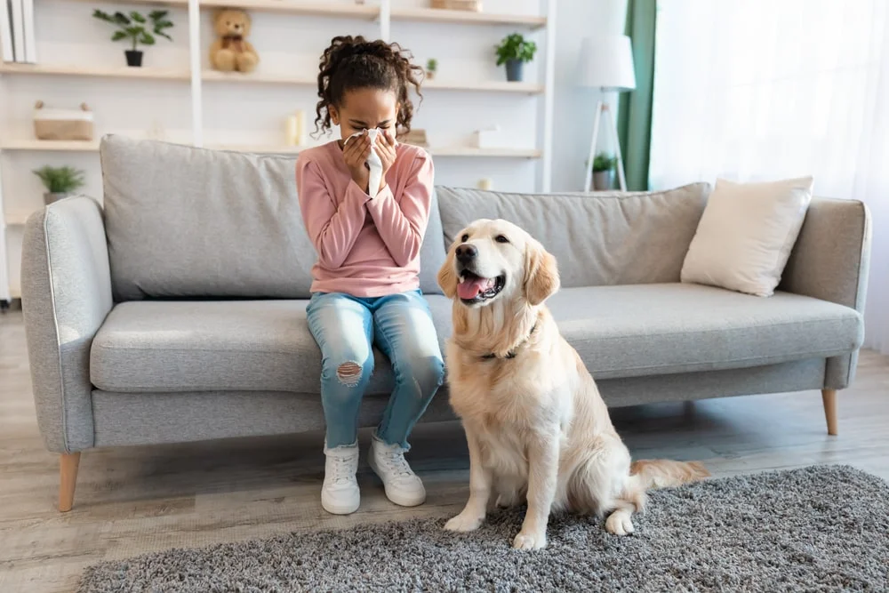 girl sneezing behind her dog