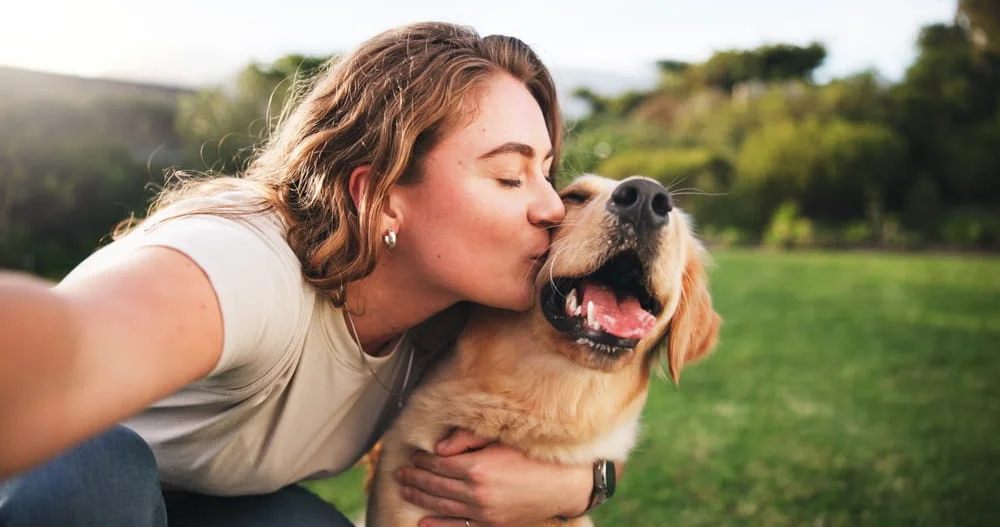 Woman giving her dog a kiss in a field