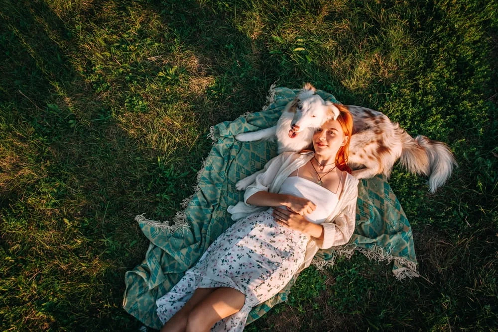 woman laying in the field with her dog