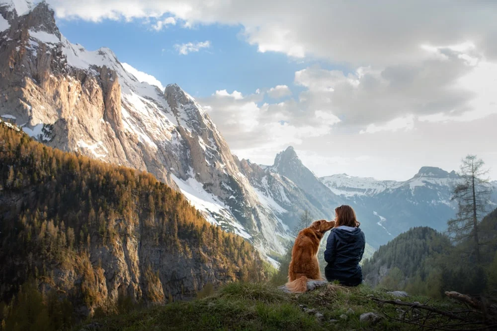 Woman kisses her dog in the mountains