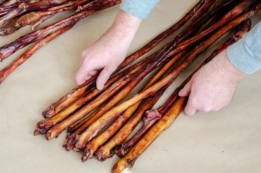 A man’s hands organizing a bundle of bully sticks.