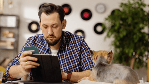 Man managing finances at home with his dog nearby.